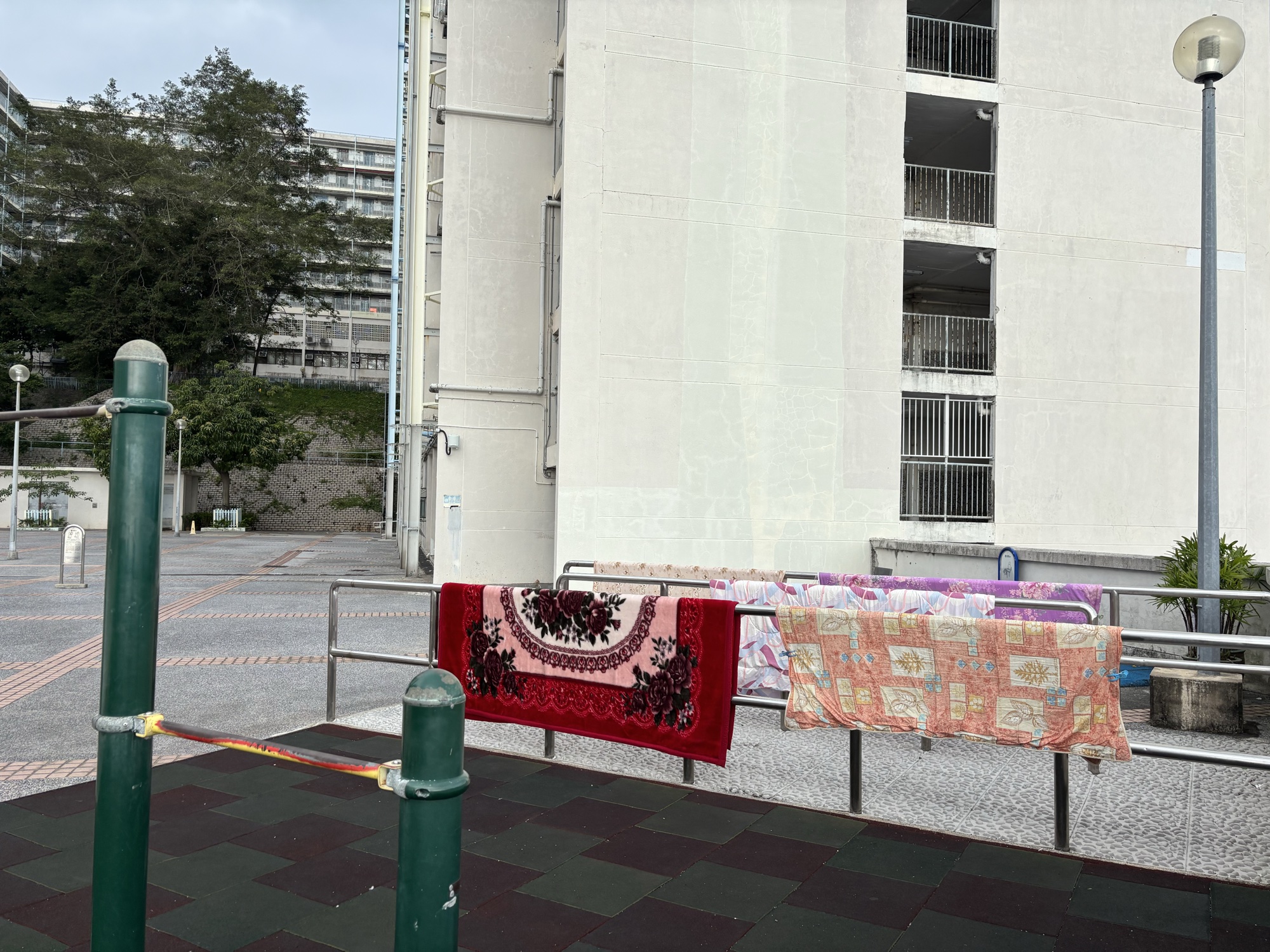 Traces of Life — carpets aired over a railing in the shared space of a Hong Kong public housing estate; everyday traces of inhabitation